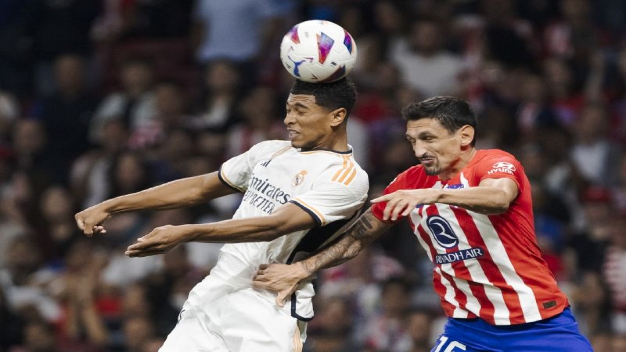Pemain Real Madrid Jude Bellingham (kiri) dan pemain Atletico Madrid Stefan Savic berebut bola saat pertandingan Liga Spanyol kedua tim di Civitas Metropolitano Stadium, Madrid, Spanyol, Minggu (24/9/2023) (Photo by Guille Martinez/AFLO)