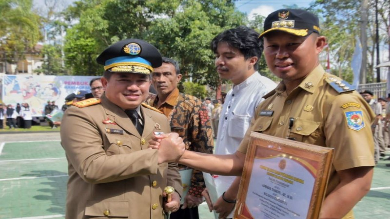 Kepala Kanwil BPN Provinsi Sultra Asep Heri saat menyerahkan penghargaan kepada Pj Wali Kota Kendari Asmawa Tosepu. (Antara/La Ode Muh Deden Saputra)