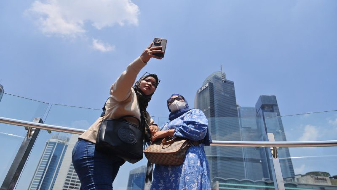 Wisatawan berfoto di kawasan Bundaran HI dengan latar belakang langit biru di Jakarta, Selasa (12/9/2023). Setelah sempat mencapai angka 172 atau masuk dalam kategori tidak sehat berdasarkan data IQAir, kualitas udara Jakarta hari ini pada pukul 12.31 membaik di angka 105 atau tidak sehat untuk kelompok yang sensitif. ANTARA FOTO/Akbar Nugroho Gumay/rwa. (ANTARA FOTO/AKBAR NUGROHO GUMAY)