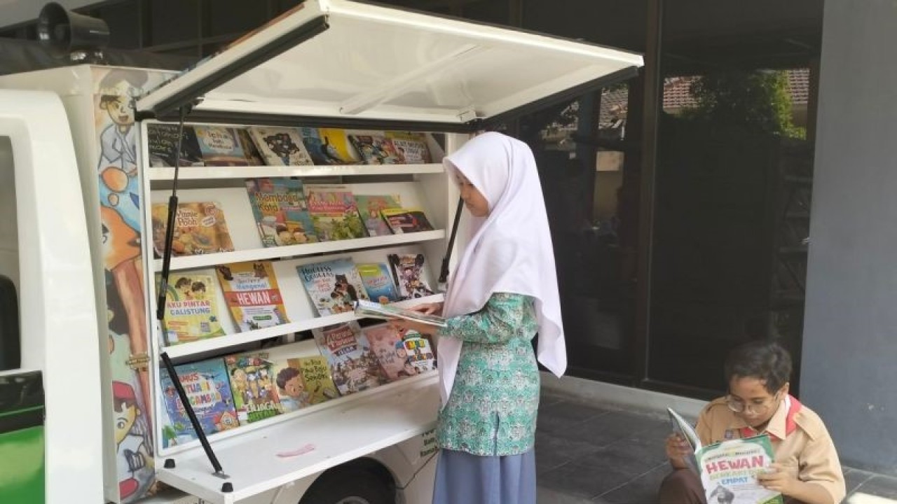 Dua orang siswa membaca buku di perpustakaan keliling di Solo, Jawa Tengah, Kamis (14/9/2023). ANTARA/Aris Wasita