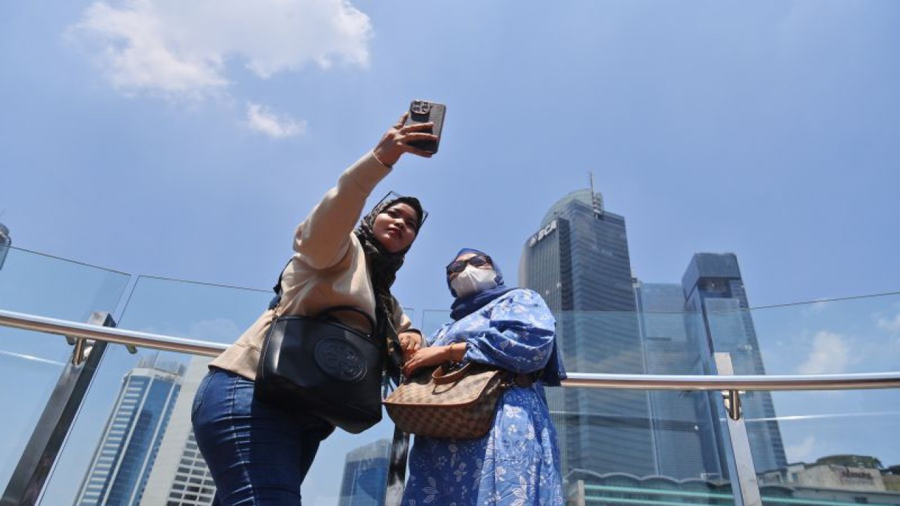 Wisatawan berfoto di kawasan Bundaran HI dengan latar belakang langit biru di Jakarta, Selasa (12/9/2023). Setelah sempat mencapai angka 172 atau masuk dalam kategori tidak sehat berdasarkan data IQAir, kualitas udara Jakarta hari ini pada pukul 12.31 membaik di angka 105 atau tidak sehat untuk kelompok yang sensitif. ANTARA FOTO/Akbar Nugroho Gumay/rwa.