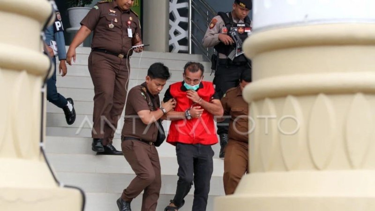 Arsip - Mantan Wali Kota Lhokseumawe Suaidi Yahya (tengah) dengan tangan diborgol berjalan menuju mobil tahanan usai menjalani pemeriksaan di kantor Kejaksaan Negeri Lhokseumawe, Aceh, Senin (22/5/2023). ANTARA FOTO/Rahmad.