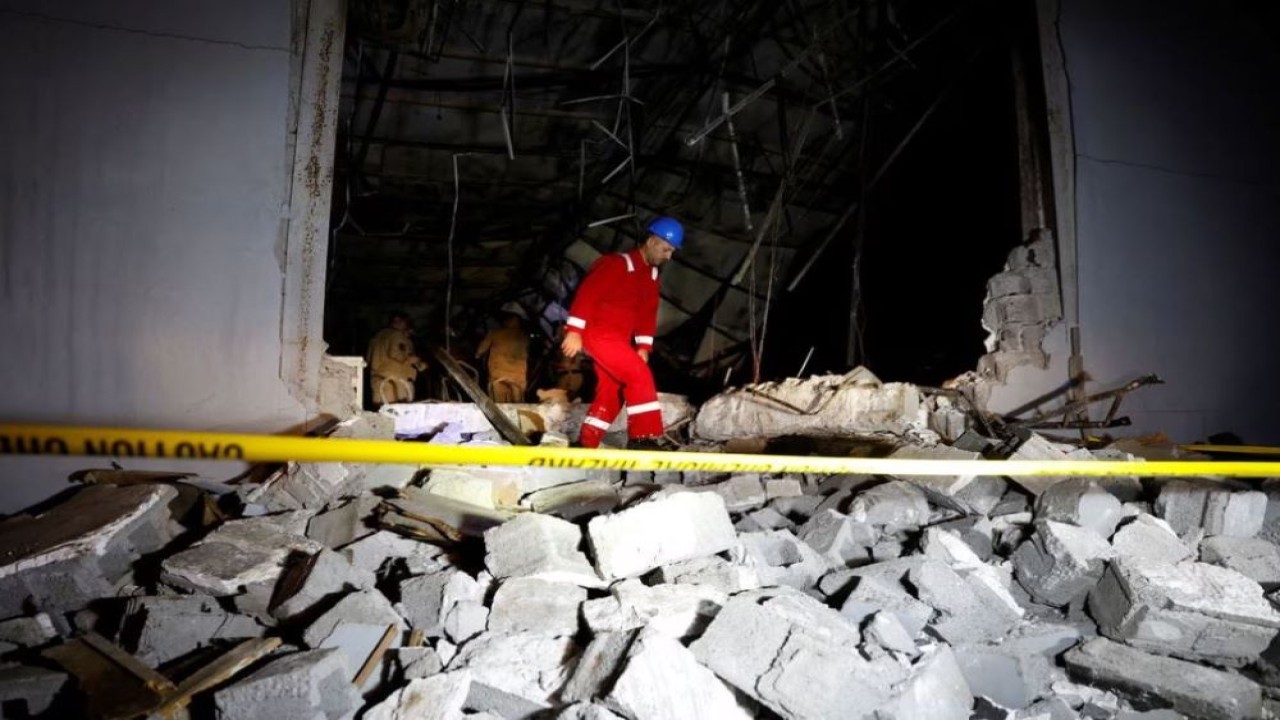 Seorang pekerja darurat berjalan di atas puing-puing di lokasi menyusul kebakaran besar pada perayaan pernikahan, di distrik Hamdaniya di Provinsi Nineveh, Irak, pada 27 September 2023. (Khalid Al-Mousily/Reuters)