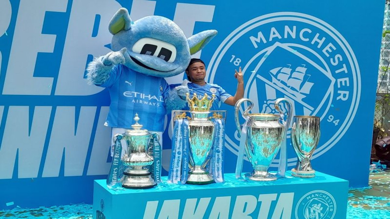 Suporter Manchester City berfoto dengan trofi klub dalam acara bertajuk "Treble Trophy Tour" yang berlangsung di Menara Imperium, Jakarta, Sabtu (30/09/2023). (ANTARA/FAJAR SATRIYO)