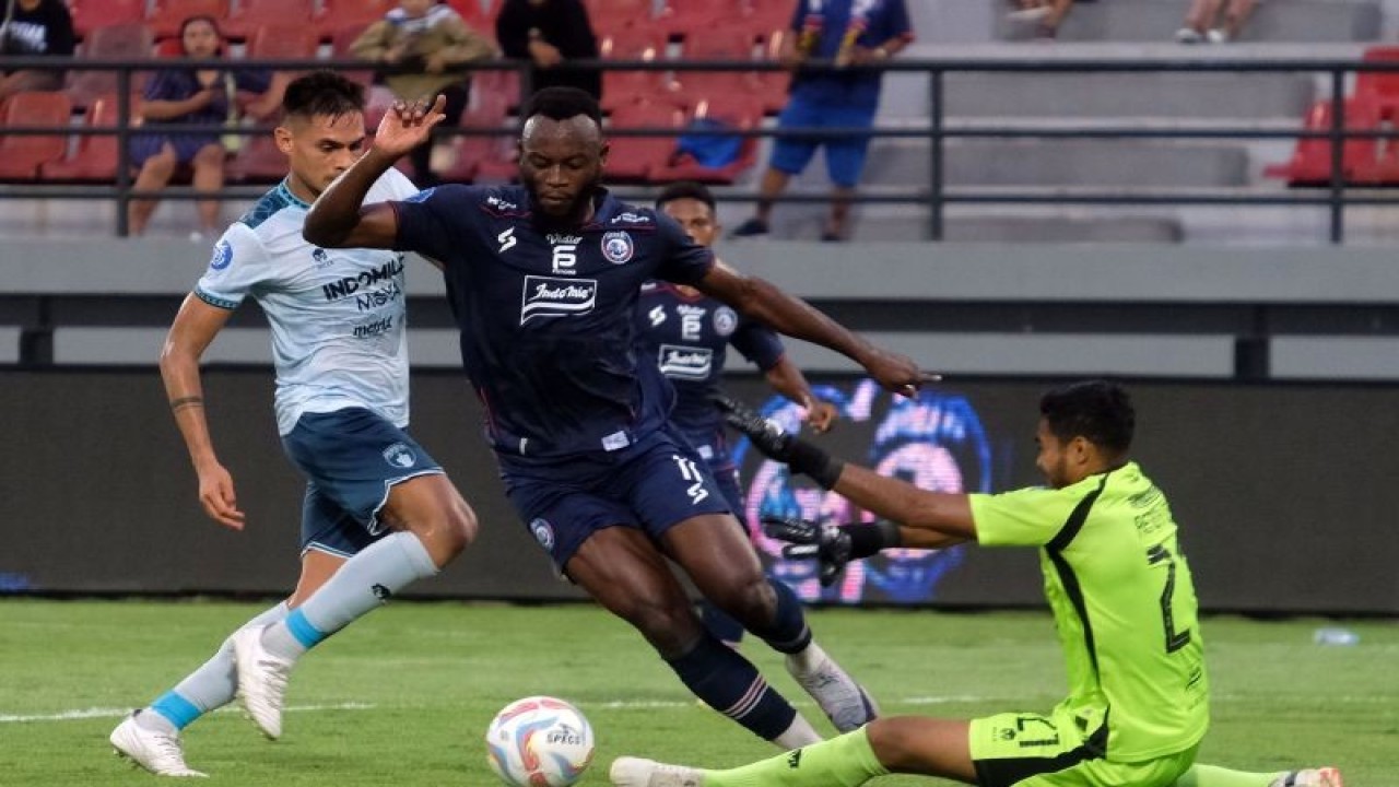 Pesepak bola Arema FC Lokolingoy (tengah) berusaha melewati kiper Persita Rendy Oscario (kanan) saat pertandingan BRI Liga 1 di Stadion Kapten I Wayan Dipta, Gianyar, Bali, Sabtu (16/9/2023). ANTARA FOTO/Nyoman Hendra Wibowo/Spt