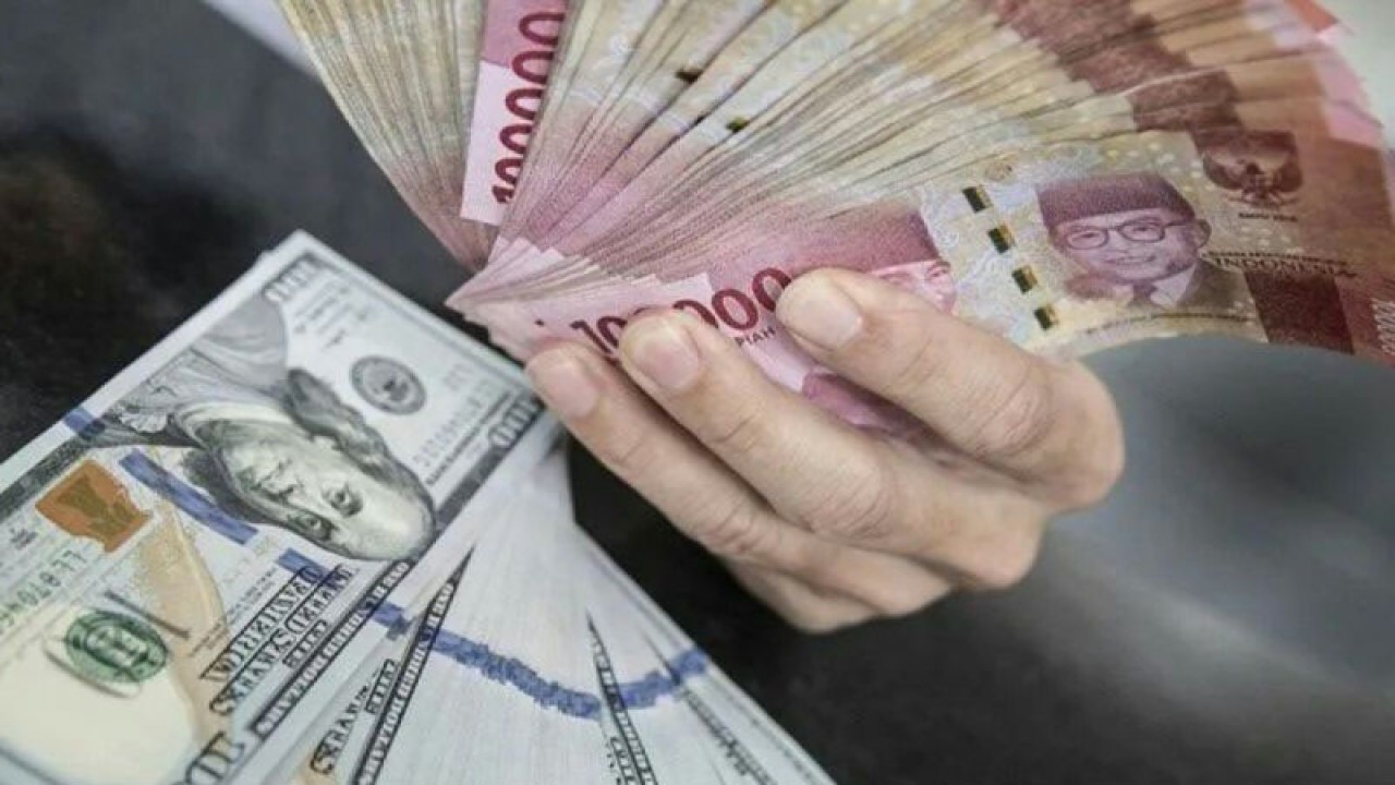 Ilustrasi petugas menunjukan uang pecahan rupiah dan dolar AS di gerai penukaran mata uang asing di Jakarta. (ANTARA FOTO/Muhammad Adimaja/foc/pri.)