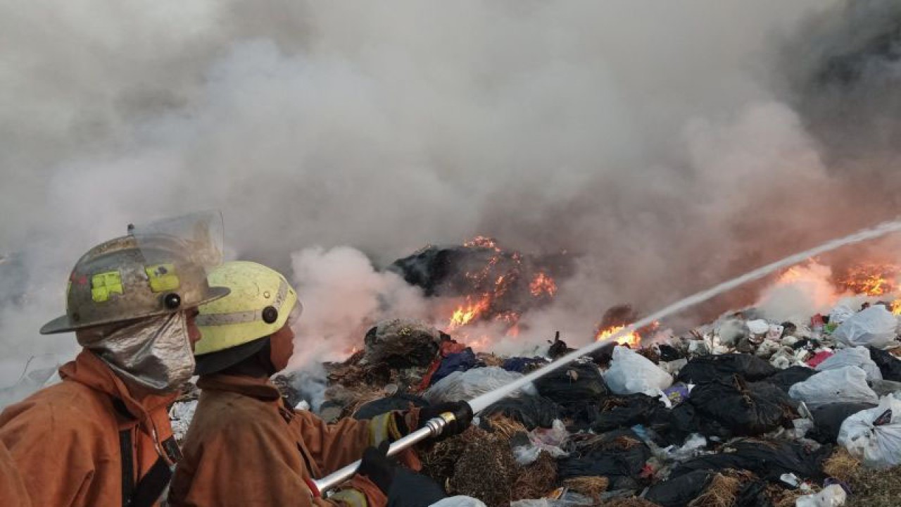 Dua petugas Damkar Kota Cirebon mengarahkan selang air ke titik api untuk memadamkan kebakaran TPA Kopi Luhur, Cirebon, Jawa Barat, Selasa (26/9/2023) pagi. (ANTARA/Fathnur Rohman)