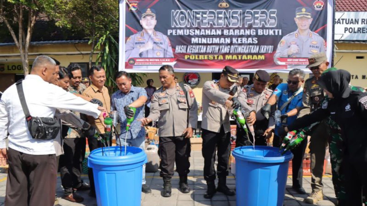 Polisi bersama pihak pemerintah menuang minuman beralkohol hasil sita dari giat rutin dalam rangka menekan gangguan keamanan dan ketertiban masyarakat ke dalam ember besar di Polresta Mataram, NTB, Jumat (1/9/2023). ANTARA/HO-Polresta Mataram