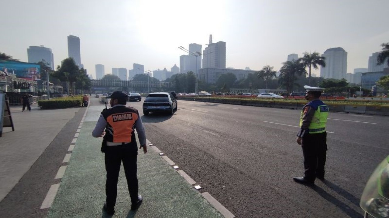 Personel dinas perhubungan dan kepolisian menutup sementara arus lalu lintas saat ada sejumlah kendaraan dari delegasi negara Kamboja di ruas Jalan Jenderal Sudirman, Jakarta Pusat, Senin (4/8/2023). (ANTARA/Bagus Ahmad Rizaldi)