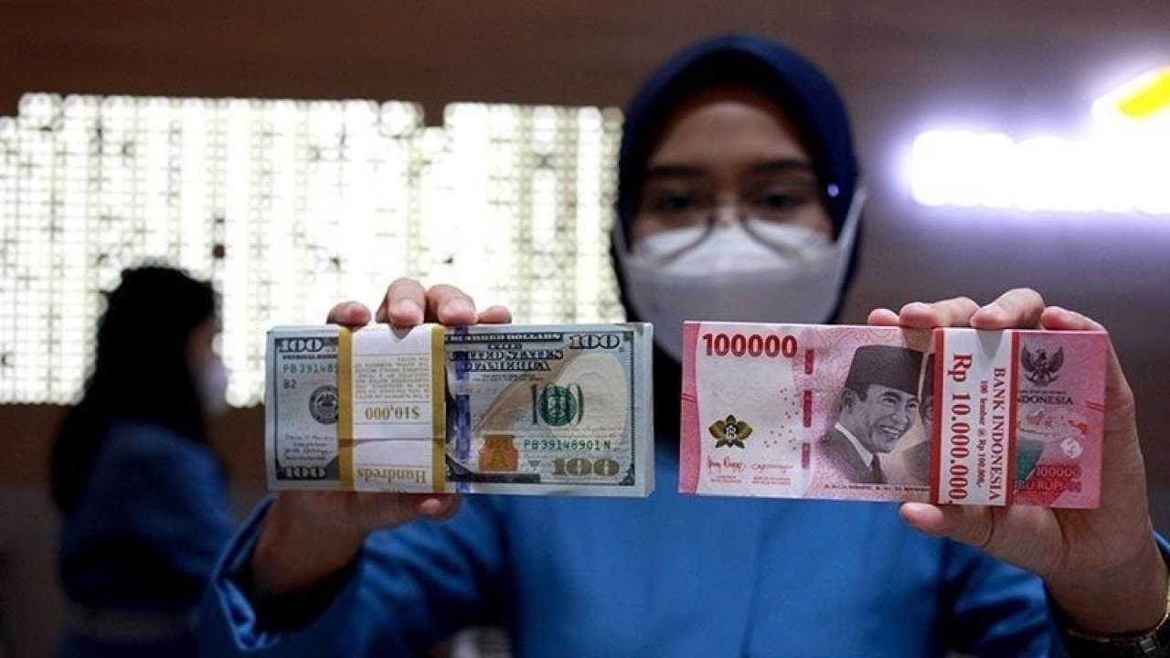 Ilustrasi - Petugas menunjukkan uang dolar AS dan uang rupiah di salah satu kantor cabang PT. Bank Mandiri Persero Tbk, Jakarta, Selasa (31/1/2023). (ANTARA FOTO/Reno Esnir/tom/pri)