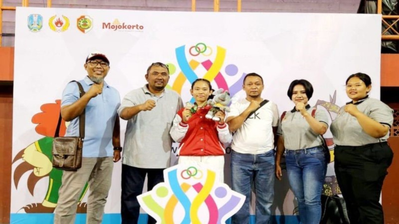 Atlet judo putri Kabupaten Sumenep, Anggi Tria Puspitasari (jaket merah) meraih medali perak di kelas 70 kilogram putri dalam Porprov Jatim 2023 berfoto bersama pelatih dan ofisial. (ANTARA/HO-KONI Sumenep)