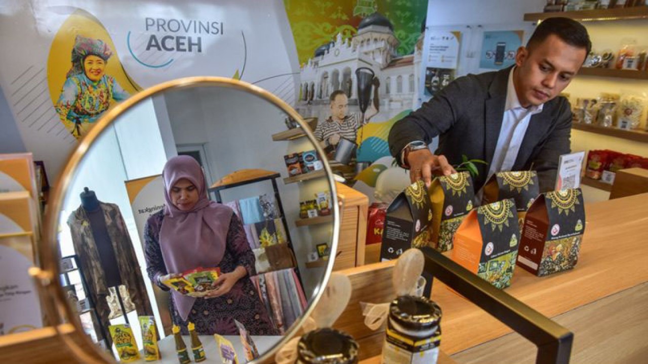 CEO Muda Rumah BUMN Aceh Helmi Fadli (kanan) menata produk UMKM binaan di BSI UMKM Center yang juga sebagai Rumah BUMN Aceh, di Banda Aceh, Aceh, Senin (4/9/2023). ANTARA/FB Anggoro