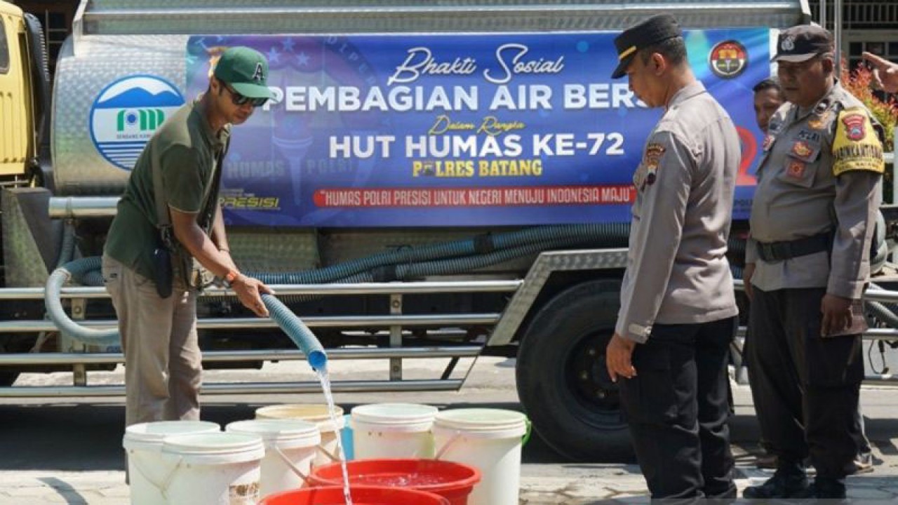 Kepala Seksi Humas Polres Batang AKP Busono (kanan) sedang membantu menyalurkan air bersih pada warga terdampak kekeringan di Kelurahan Proyonangan, Batang, Rabu (4/10/2023). (ANTARA/Kutnadi)