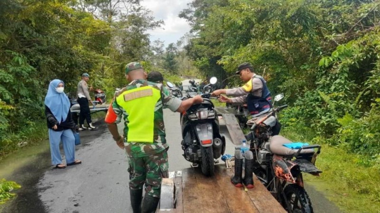 Aparat kepolisian dan TNI membantu warga melintasi bagian jalan yang tergenang di Ateung Teupat, Kecamatan Bubon, Kabupaten Aceh Barat, Provinsi Aceh, Jumat (20/10/2023). (ANTARA/HO Polsek Bubon)