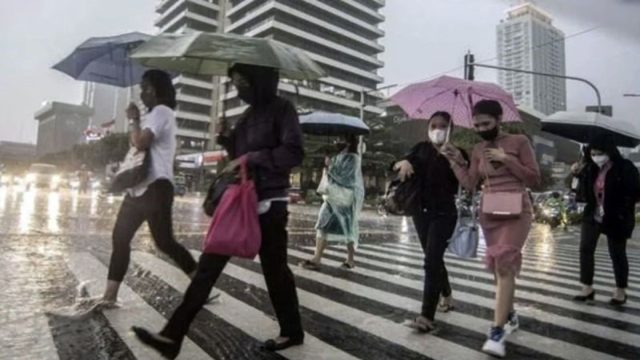 Ilustrasi - Sejumlah karyawati menyeberangi jalan yang tergenang air di depan gedung perkantoran saat hujan ringan. (ANTARA/Muhammad Adimaja/am)
