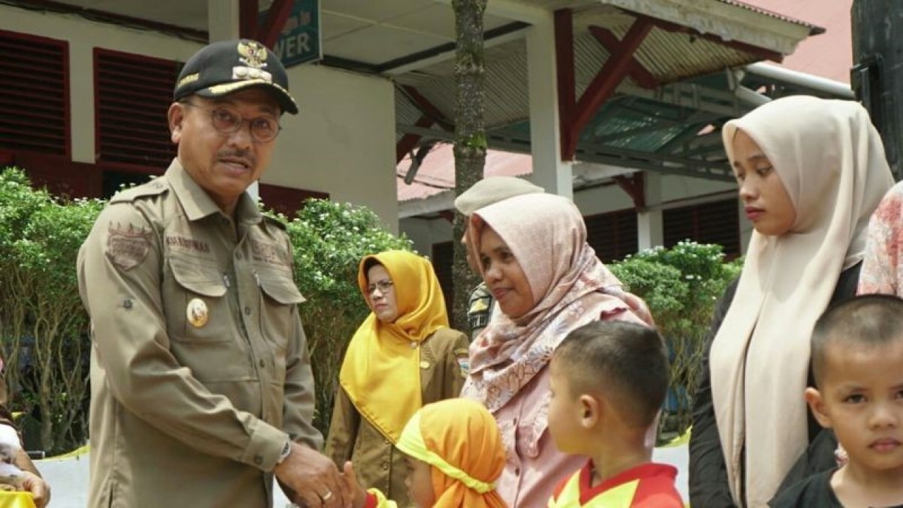Bupati Solok Selatan Khairunas menyerahkan seragam bantuan Pemerintah Daerah kepada pelajar Taman Kanak-kanak. Antara/Erik