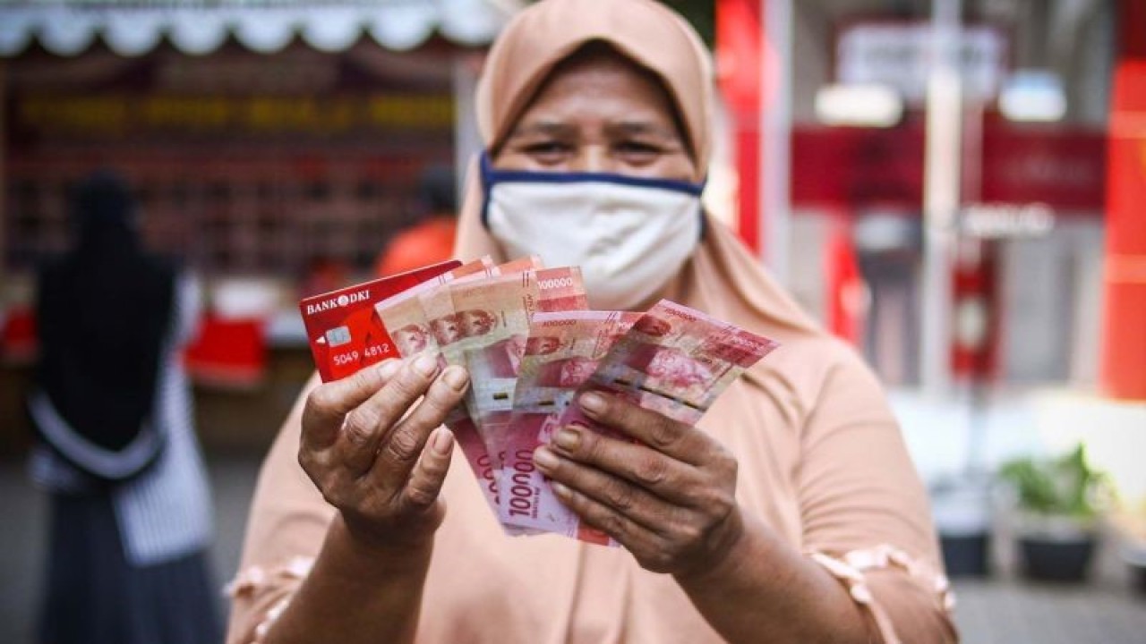 Warga menunjukkan uang bantuan sosial tunai atau BST usai mengambil di ATM Bank DKI, Jakarta, Selasa (20/7/2021). Pemprov DKI menyiapkan anggaran Rp604 miliar untuk bantuan sosial tunai atau BST kepada 1 juta Kepala Keluarga (KK) penerima manfaat selama PPKM darurat. Nilai BST kali ini mencapai Rp600.000 per KK dari hasil rapelan penyaluran tahap 5 dan 6 yang sempat tertunda pada Mei-Juni 2021 lalu. ANTARA FOTO/Rivan Awal Lingga/aww.
