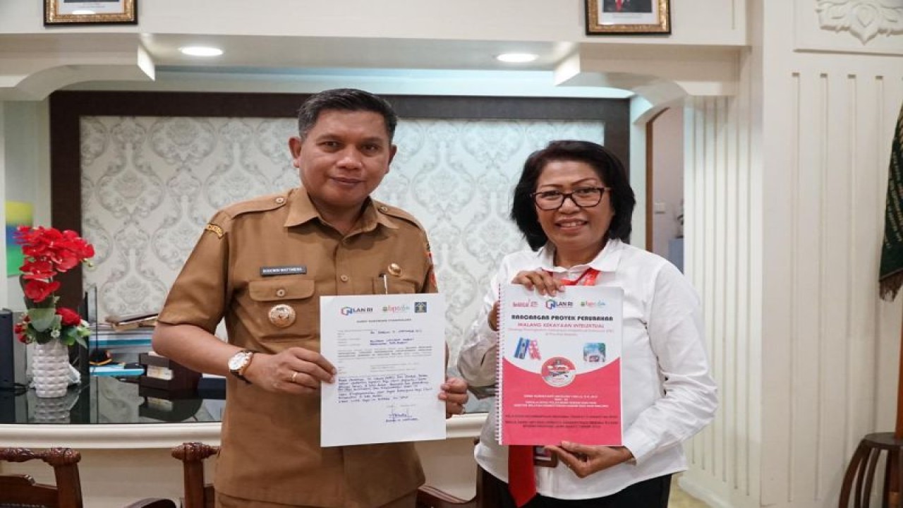 Divisi Pelayanan Hukum dan HAM Kantor Wilayah Kementerian Hukum dan Hak Asasi Manusia  Maluku Erni menyerahkan rancangan program Walang KI kepada PJ Wali Kota Ambon Bodewin Wattimena. (Antara/John Soplanit)