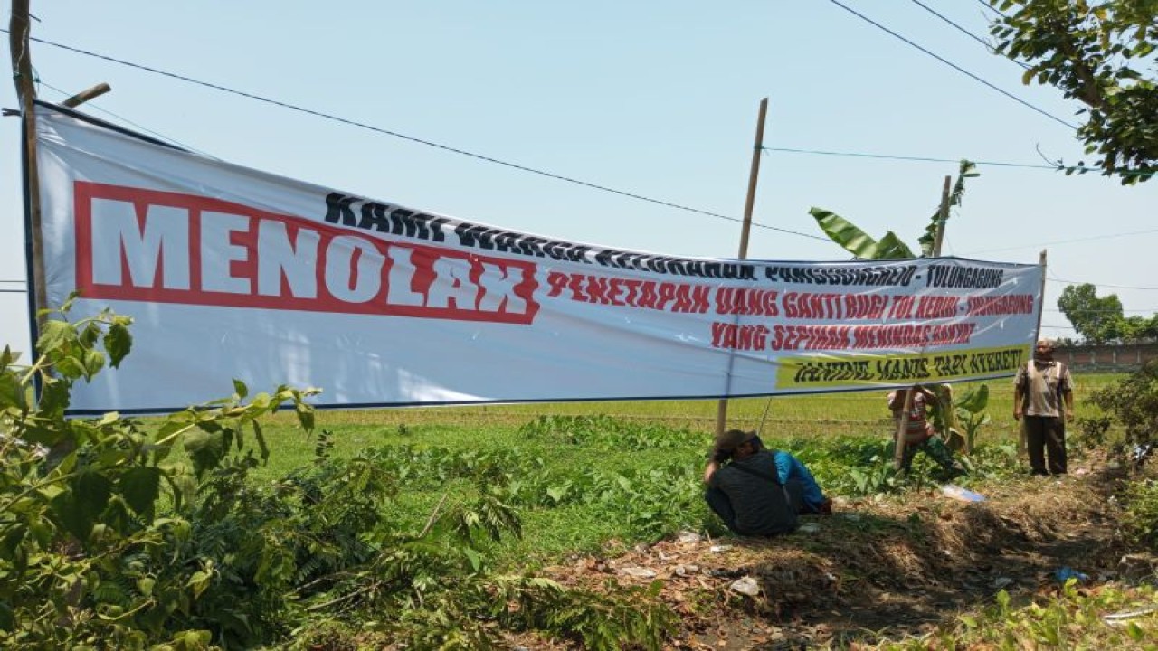 Warga memasang spanduk penolakan ganti rugi lahan terdampak Tol Tulungagung-Kediri di Tulungagung, Jawa Timur, Minggu (29/10/2023). ANTARA/HO-Joko Pramono