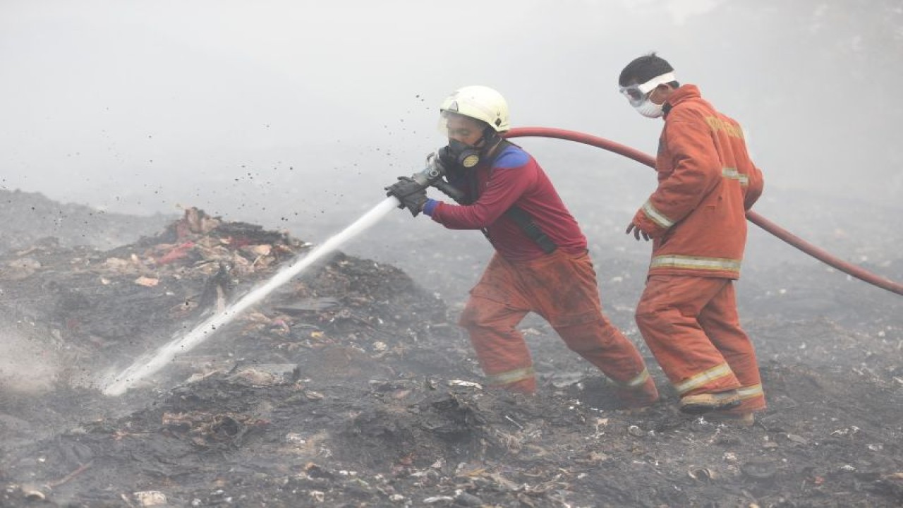 Dua petugas sedang melakukan pemadaman dengan titik yang masing mengeluarkan asap pekat di TPA Rawa Kucing, Tangerang. ANTARA/HO-Pemkot