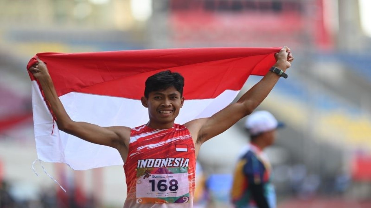 Pelari Indonesia Saptoyogo Purnomo membentangkan bendera usai mencapai garis finis pada final lari 400 meter putra T37 ASEAN Para Games 2022 di Stadion Manahan, Solo, Jawa Tengah, Rabu (3/8/2022). . ANTARA FOTO/Hendra Nurdiyansyah/tom.