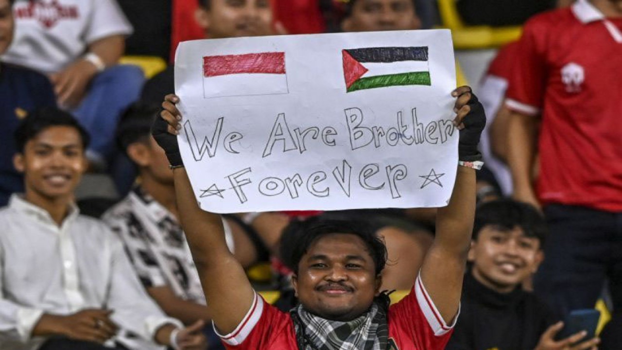 Arsip - Seorang suporter Indonesia membawa poster bertuliskan dukungan untuk Palestina saat pertandingan FIFA matchday di Stadion Gelora Bung Tomo Surabaya, Rabu (14/6/2023) malam. (ANTARA FOTO/Muhammad Adimaja)