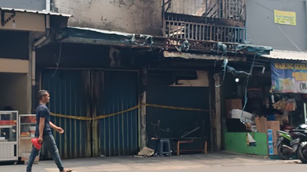 Seorang warga melintas di depan bangunan yang hangus terbakar di Jakarta, Senin (2/10/2023). (ANTARA/Khaerul Izan)