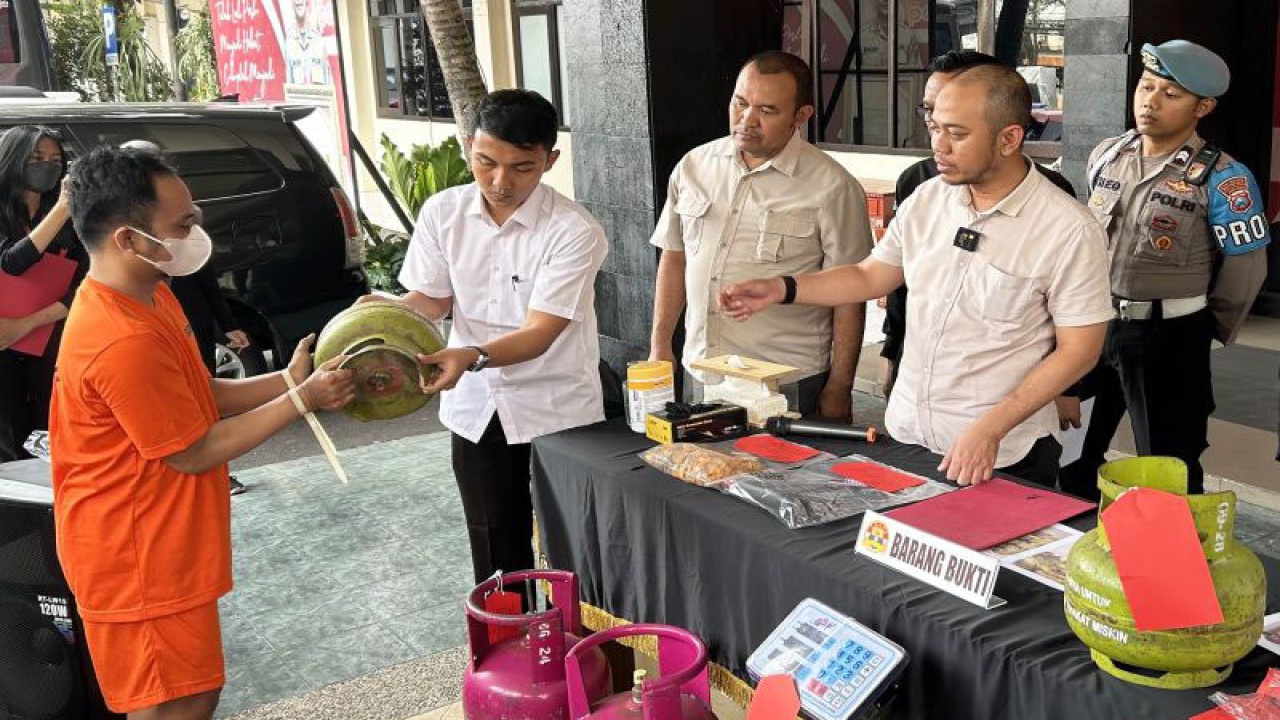 Kasat Reskrim Polresta Malang Kota Kompol Danang Yudanto (kedua kanan) menyaksikan tersangka HS (kiri) memeragakan praktik pemindahan gas elpiji bersubsidi dari tabung tiga kilogram ke tabung 5,5 kilogram, di Mapolresta Malang Kota, Jawa Timur, Selasa (7/11/2023). ANTARA/Vicki Febrianto.