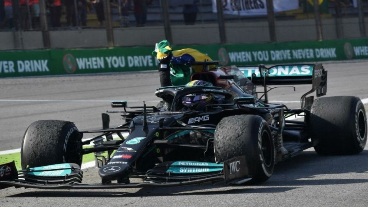 Pebalap Mercedes Lewis Hamilton melakukan selebrasi dengan mengibarkan bendera Brasil setelah memenangi Grand Prix Sao Paulo, Autodromo Jose Carlos Pace, Interlagos. (14/11/2021) (AFP/NELSON ALMEIDA)