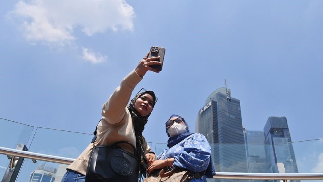 Arsip Foto - Warga berswafoto dengan latar belakang gedung dan langit biru di kawasan Bundaran HI, Jakarta, Selasa (12/9/2023). ANTARA FOTO/Akbar Nugroho Gumay/Spt.