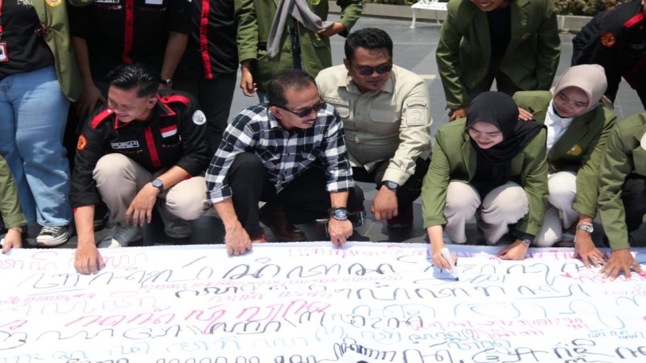 Wakil Ketua DPRD Kota Surabaya AH Thony bersama mahasiswa UPN Veteran Jatim menuliskan aksara Jawa pada kain putih yang dibentangkan di Balai Pemuda Surabaya, Selasa (31/10/2023), dalam upaya pelestarian budaya Jawa.  (ANTARA/HO-DPRD Surabaya)
