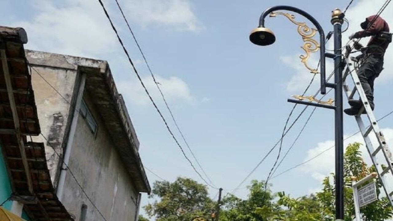 Pekerja sedang memasang penerangan jalan umum di salah satu gang di Kota Madiun, Jatim yang merupakan pelaksanaan program lampunisasi. ANTARA/HO-Diskominfo Kota Madiun.