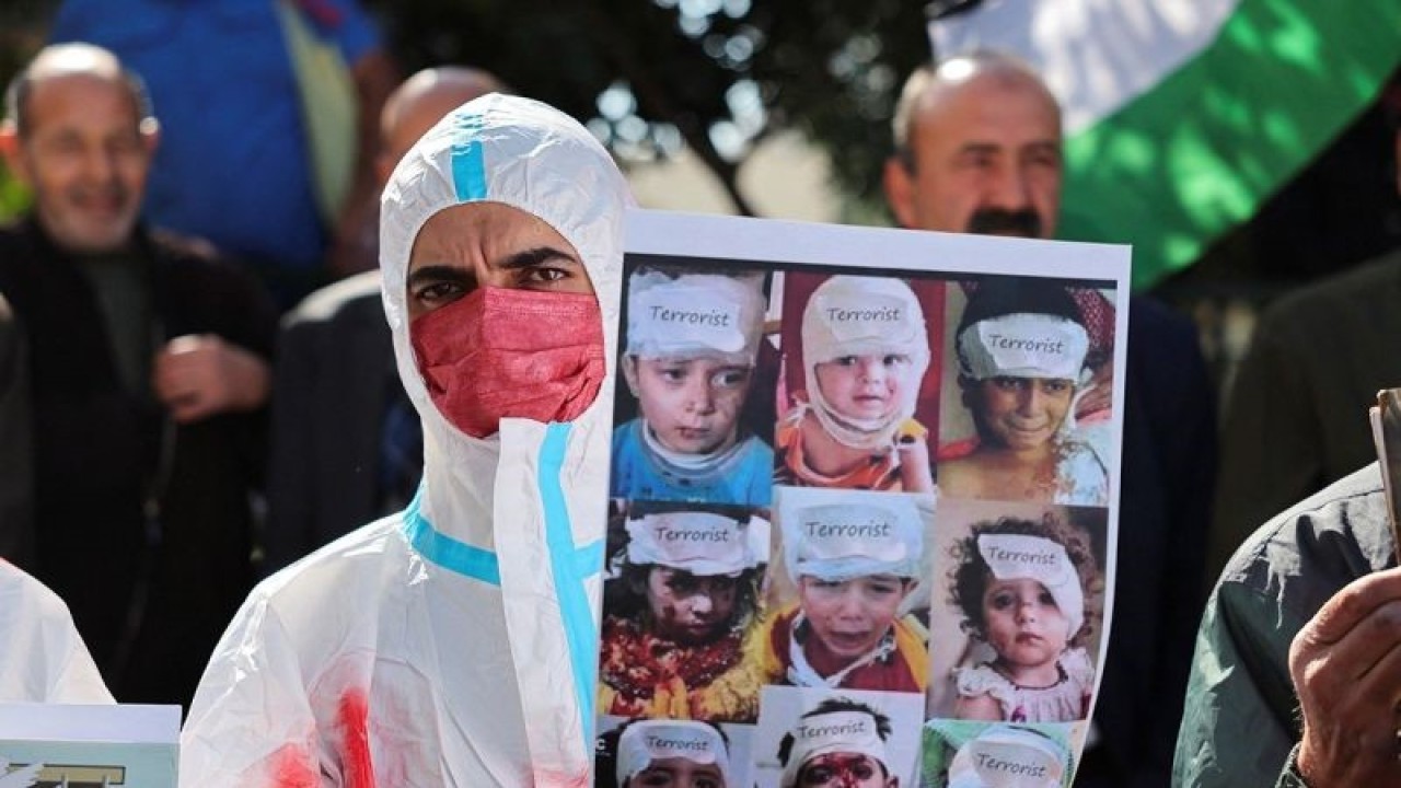 Seorang pengunjuk rasa yang mengenakan kain kafan memegang plakat selama protes solidaritas terhadap tahanan Palestina di penjara-penjara Israel ketika konflik antara Israel dan kelompok Islam Palestina Hamas berlanjut, di Hebron, di Tepi Barat yang diduduki Israel (14/11/2023). ANTARA/REUTERS/Mussa Qawasma/aa. (REUTERS/MUSSA ISSA QAWASMA)