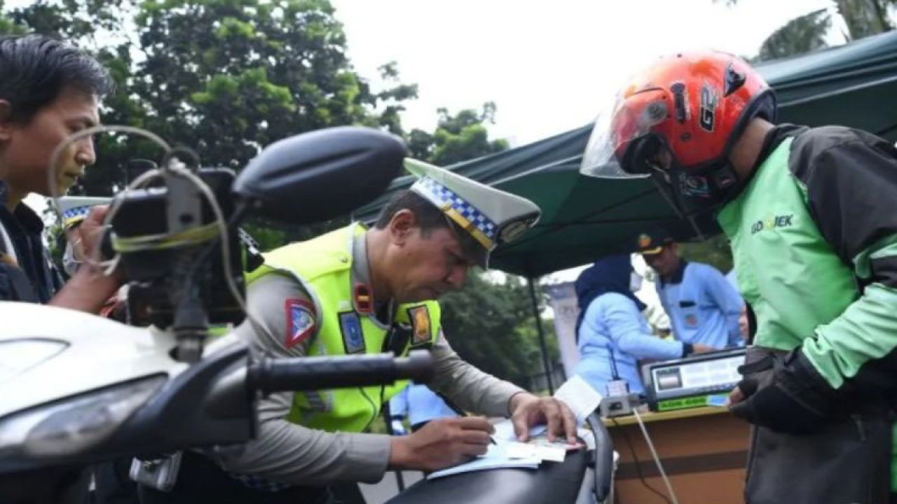 Anggota Kepolisian menulis surat tilang bagi pengendara motor yang kendaraannya tidak lulus uji emisi saat razia di Lebak Bulus, Jakarta Selatan, Rabu (1/11/2023). ANTARA FOTO/Sigid Kurniawan/nym
