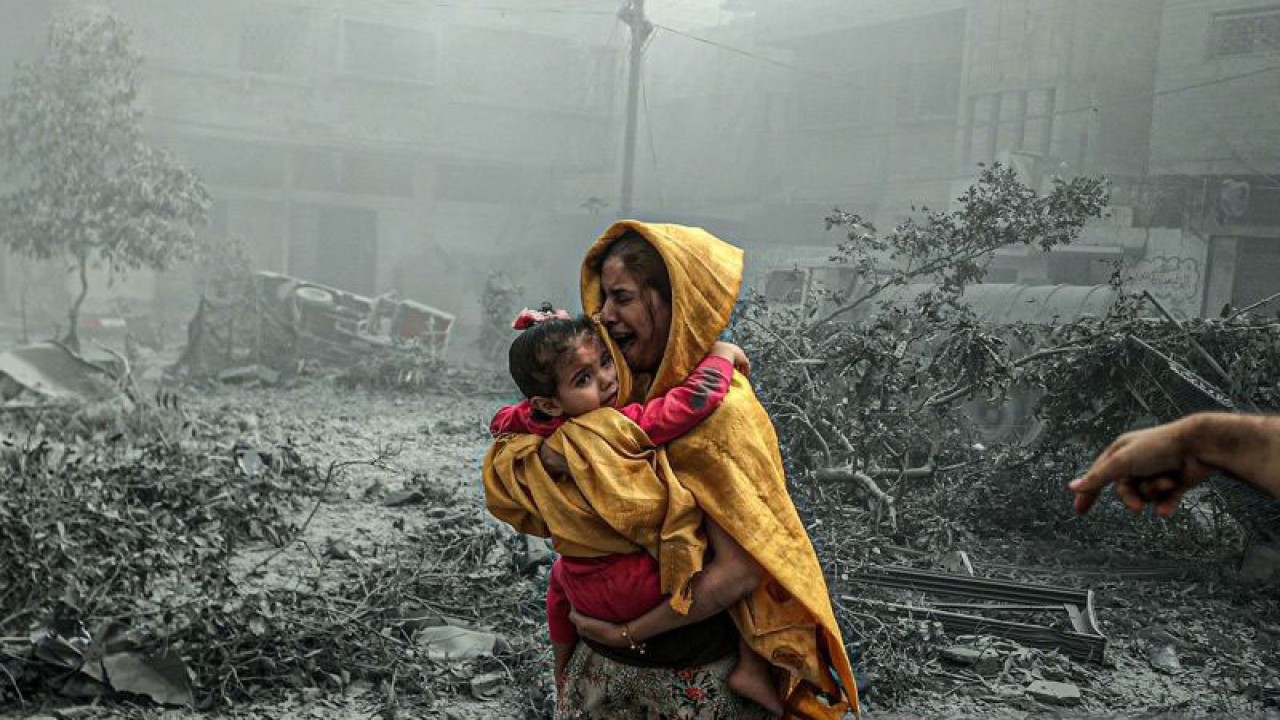 Seorang wanita menggendong seorang gadis bereaksi setelah serangan udara Israel menghantam lingkungan Ridwan di Kota Gaza, Gaza pada 23 Oktober 2023. ANTARA/Ali Jadallah / Anadolu/pri. (Anadolu via Reuters Connect/Ali Jadallah)