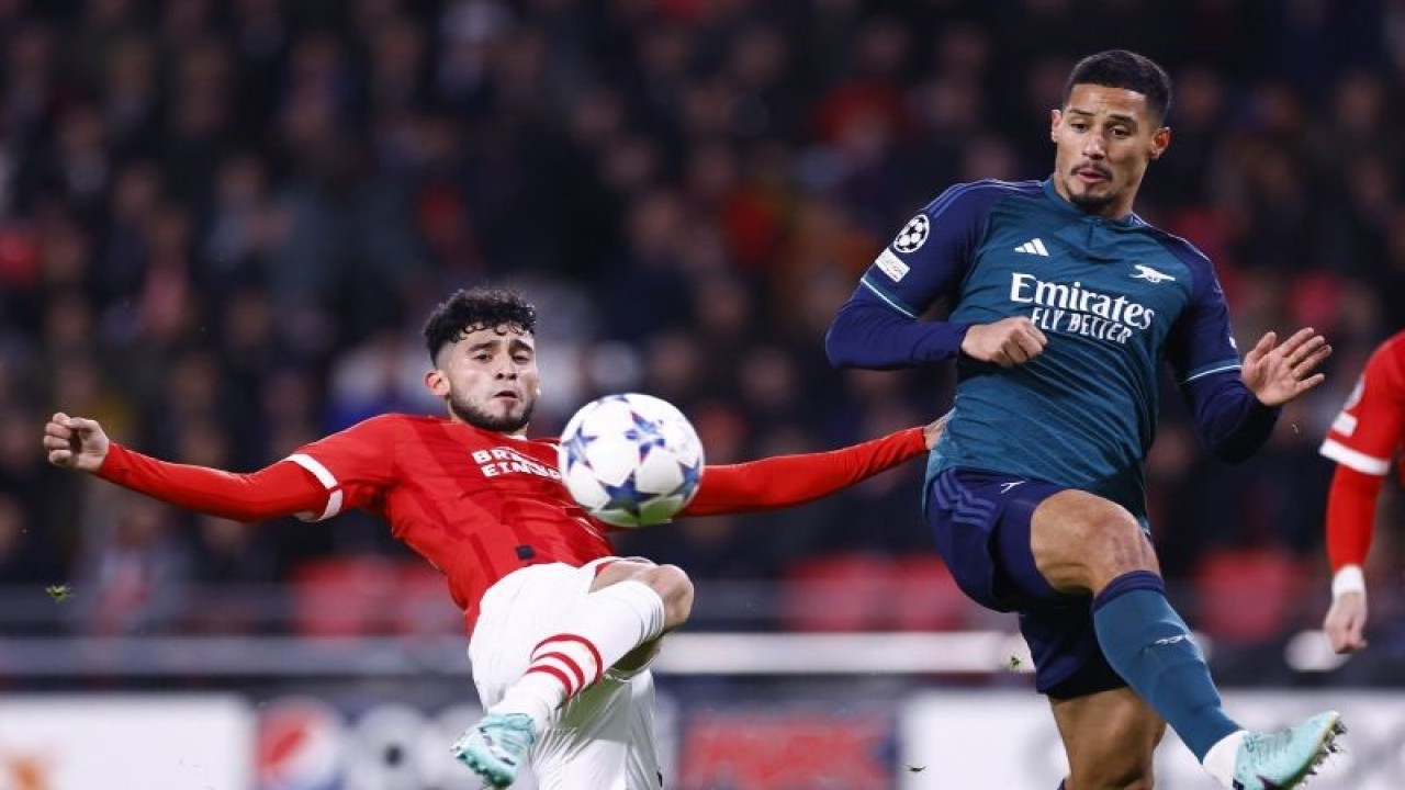 Penyerang PSV Eindhoven Ricardo Pepi (kiri) berduel memperebutkan bola dengan bek Arsenal William Saliba (kanan) pada pertandingan Grup B Liga Champions yang dimainkan di Stadion Philips, Eindhoven, Selasa (12/12/2023). (ANTARA/AFP/KENZO TRIBOUILLARD)