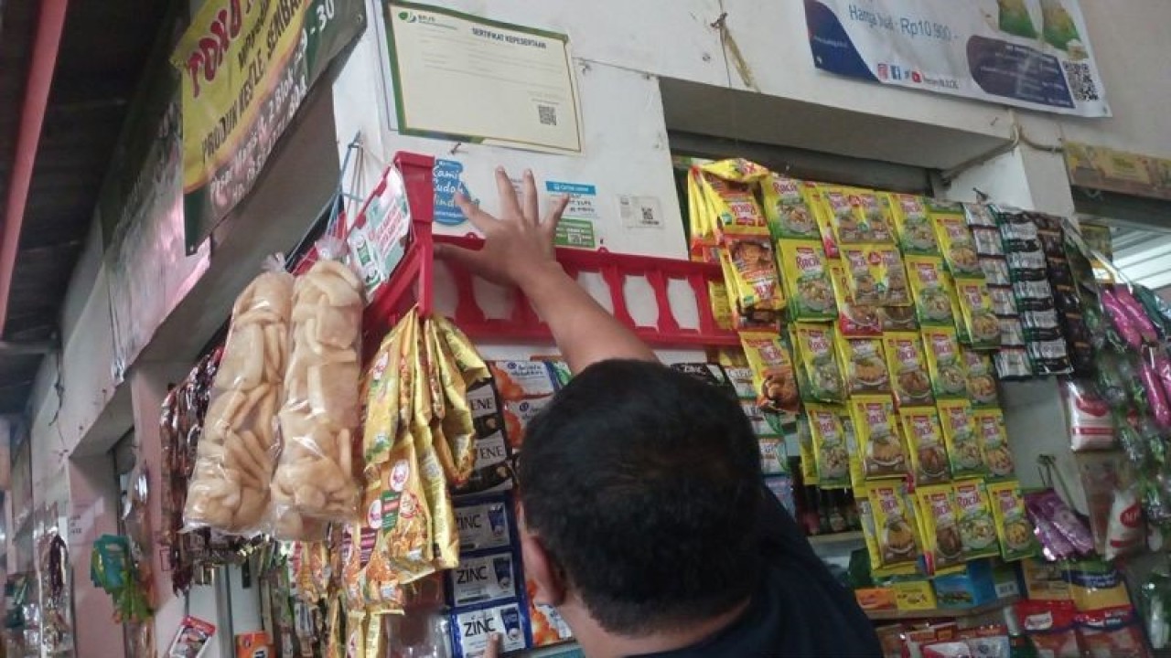 Kepala Cabang BPJS Ketenagakerjaan Purwokerto Antony Sugiarto menempelkan stiker tanda kepesertaan program BPJAMSOSTEK pada dinding salah satu kios di Pasar Manis, Purwokerto, Kabupaten Banyumas, Rabu (20/12/2023). ANTARA/Sumarwoto