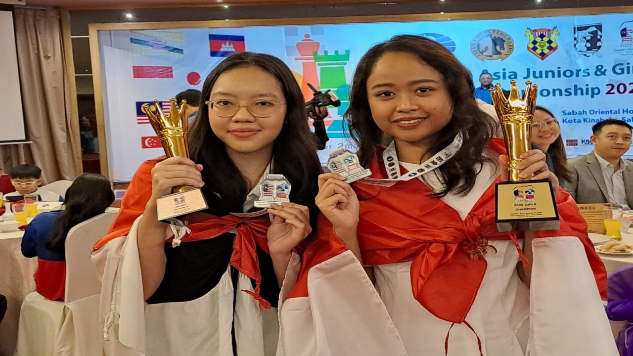 Diajeng Teresa Singgih (kanan) dan Cecilia Natalie Liuviann dengan berbalut bendera Merah Putih memperlihatkan thropy juara dan peringkat tiga Kejuaraan Catur Junior Asia Timur 2023 di Kinabalu, Sabah, Malaysia/Foto: Kristianus Liem