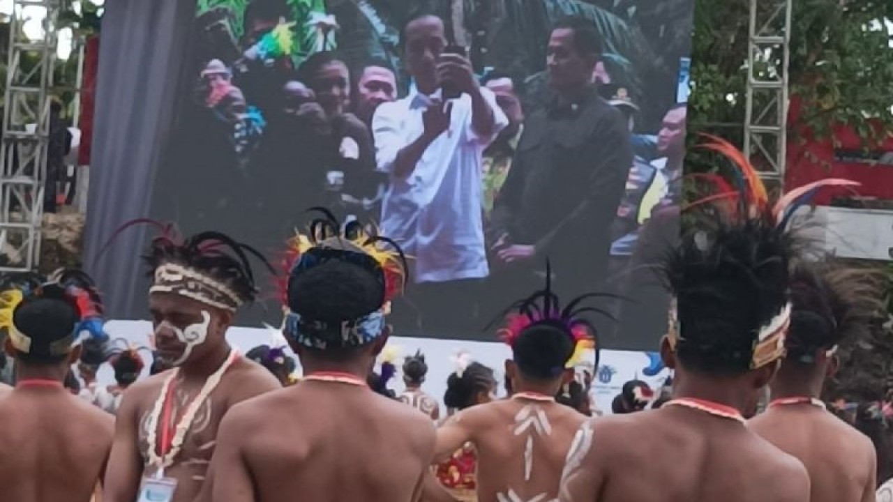 Pemuda Biak menggunakan simbol adat topi mahkota menyaksikan Presiden Joko Widodo melakukan foto selfi saat menghadiri kegiatan Sail Teluk Cenderawasih 21-27 November 2023.ANTARA/Muhsidin