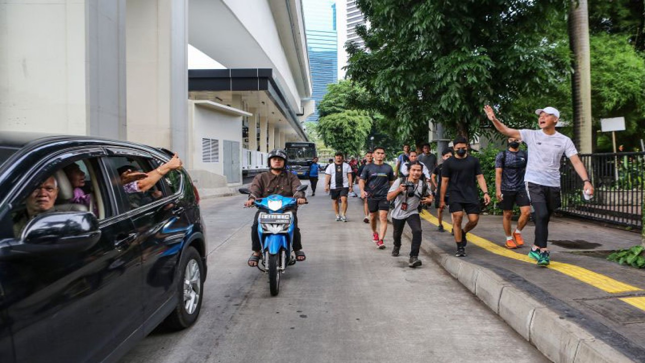 Capres nomor urut 3 Ganjar Pranowo (kanan) menyapa warga saat lari pagi di kawasan Sudirman, Jakarta, Minggu (10/12/2023). (ANTARA FOTO/Asprilla Dwi Adha/foc)
