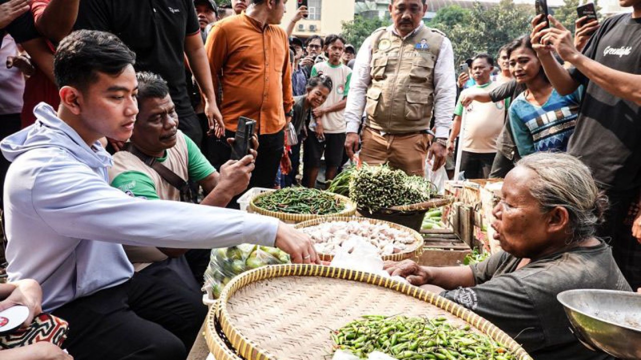 Cawapres nomor urut 2 Gibran Rakabuming Raka (kiri) berbincang dengan pedagang di los sayur mayur di Pasar Induk Kramat Jati, Jakarta, Sabtu (23/12/2023). (ANTARA/Aprillio Abdullah Akbar)