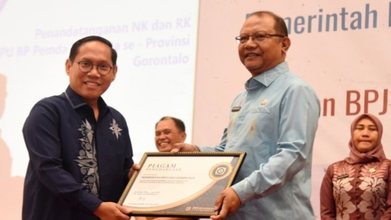 Deputi Direksi BPJS Kesehatan Wilayah X Octavianus Ramba (kiri) menyerahkan penghargaan kepada Sekda Provinsi Gorontalo Sofian Ibrahim pada penandatanganan NKRK di Gedung GPCC Kota Gorontalo, Senin (18/12/2023). (ANTARA/ HO-Diskominfotik Provinsi Gorontalo)