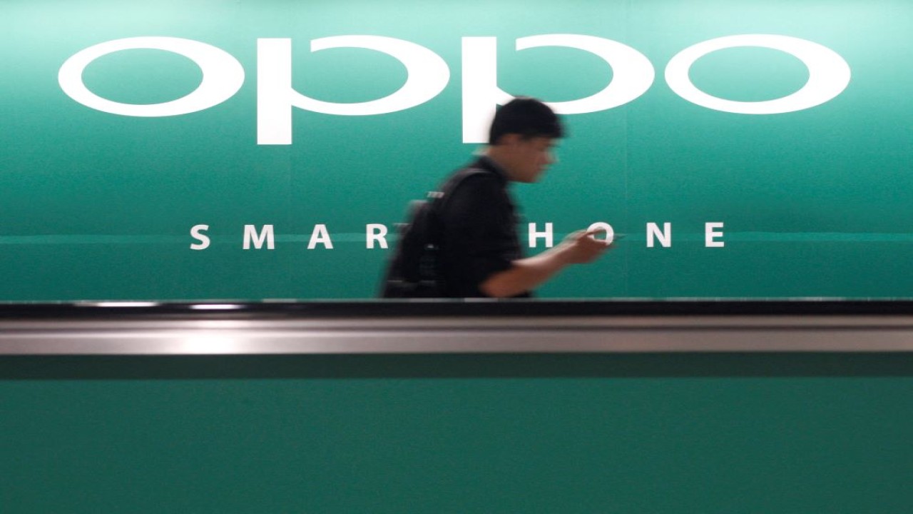 Seorang komuter yang menggunakan ponselnya melewati iklan produsen ponsel pintar asal China Oppo di stasiun kereta api di Singapura, pada 8 Mei 2014. (Edgar Su/Reuters)