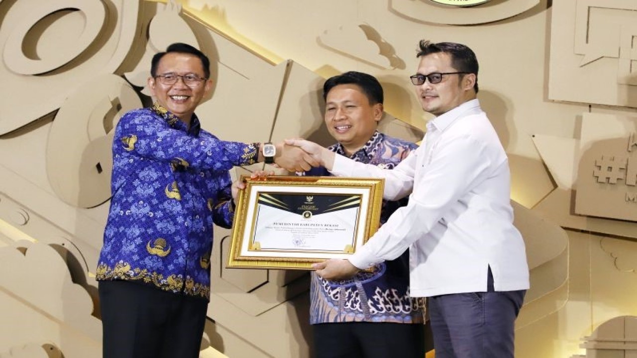 Komisioner Komisi Informasi Provinsi Jawa Barat Husni Farhani saat menyerahkan penghargaan Kabupaten Menuju Informatif kepada Pemerintah Kabupaten Bekasi atas prestasi pelayanan informasi publik tahun 2023. (ANTARA/Pradita Kurniawan Syah).