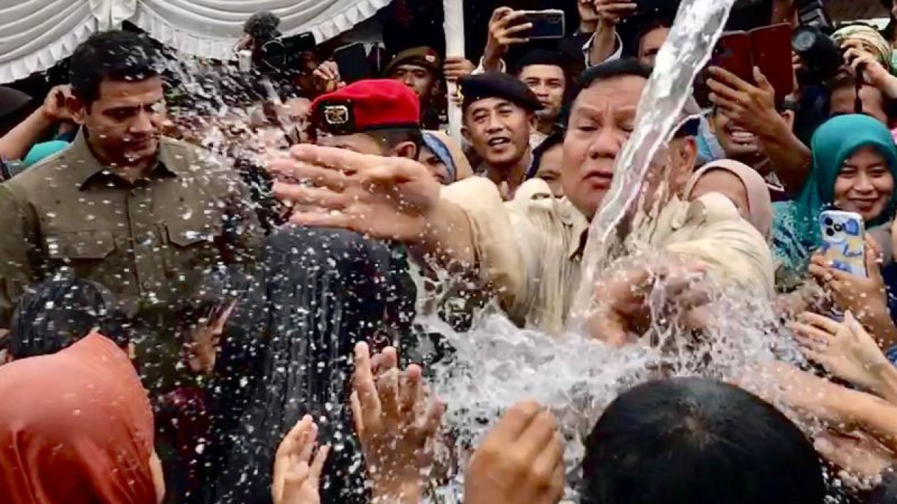 Menteri Pertahanan Prabowo Subianto menyibakkan air ke arah ibu-ibu usai penyerahan bantuan pipa buatan Universitas Pertahanan di Desa Karanganyar, Kabupaten Sukabumi, Jawa Barat, Sabtu (30/12/2023). (ANTARA/Genta Tenri Mawangi)