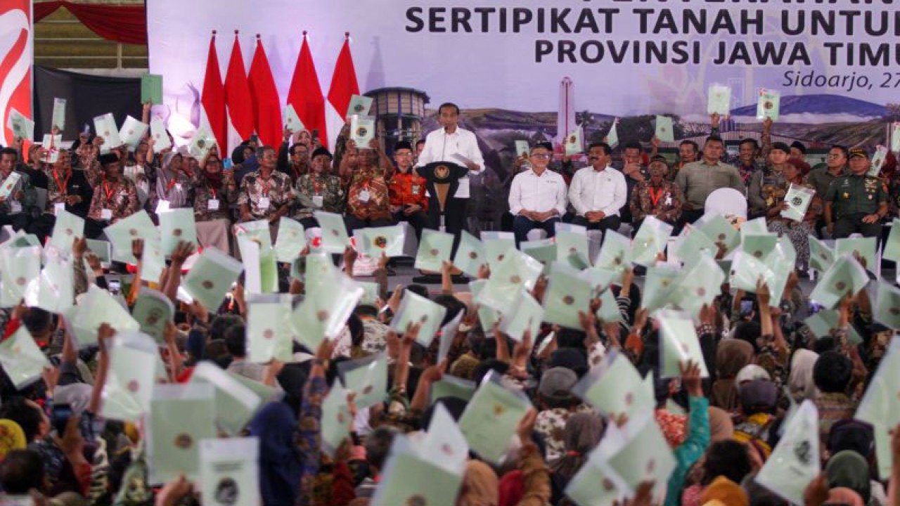 Presiden Joko Widodo (Jokowi) mengangkat sertifikat tanah warga saat penyerahan sertifikat tanah untuk rakyat Jawa Timur (Jatim) di Gelora Delta Sidoarjo, Rabu (27/12/2023). Presiden menyerahkan sertifikat tanah di Jatim sebagai upaya memberikan hak hukum bukti kepemilikan tanah kepada masyarakat penerima sertifikat. ANTARA FOTO/Umarul Faruq