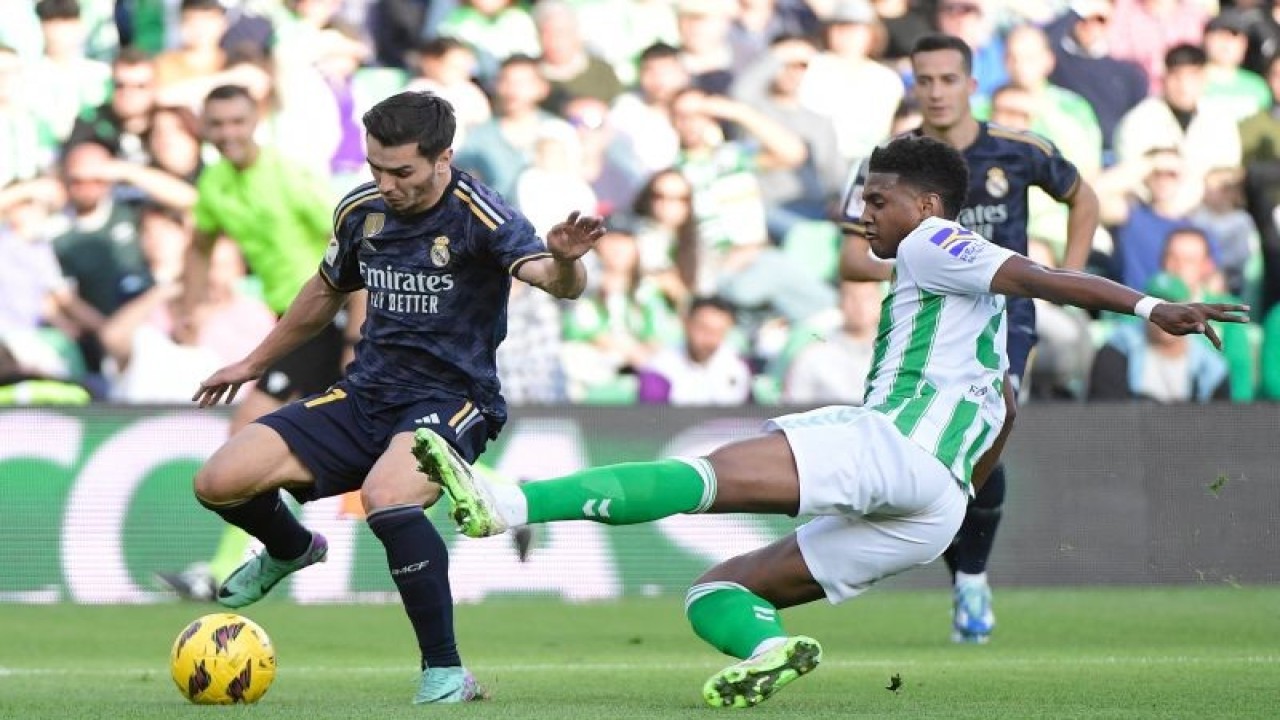 Penyerang Real Madrid Brahim Diaz (kiri) menjaga penguasaan bola dari ancaman bek Real Betis Chadi Riad (kanan) pada pertandingan Liga Spanyol yang dimainkan di Estadio Benito Villamarin, Seville, Sabtu (9/12/2023). (ANTARA/AFP/CRISTINA QUICLER)