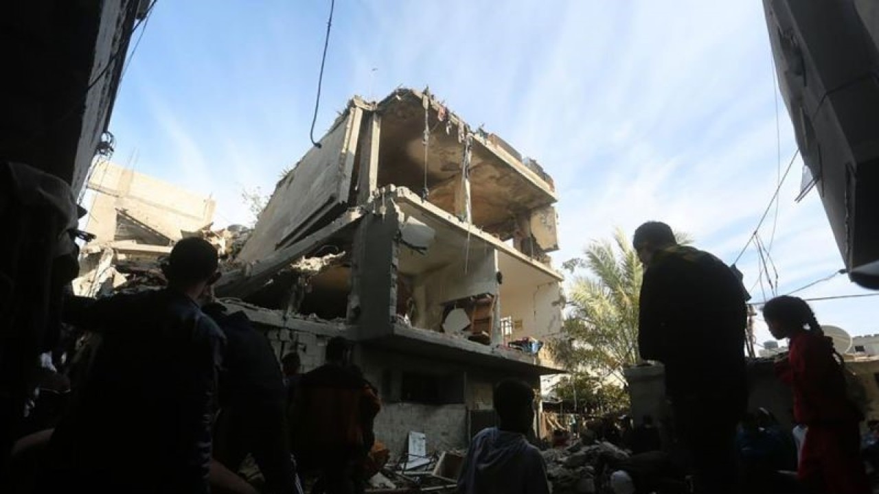 Sejumlah warga Palestina terlihat di depan sebuah bangunan yang hancur akibat serangan Israel di kota Rafah di Jalur Gaza selatan (7/12/2023).ANTARA/Xinhua/Khaled Omar/aa.