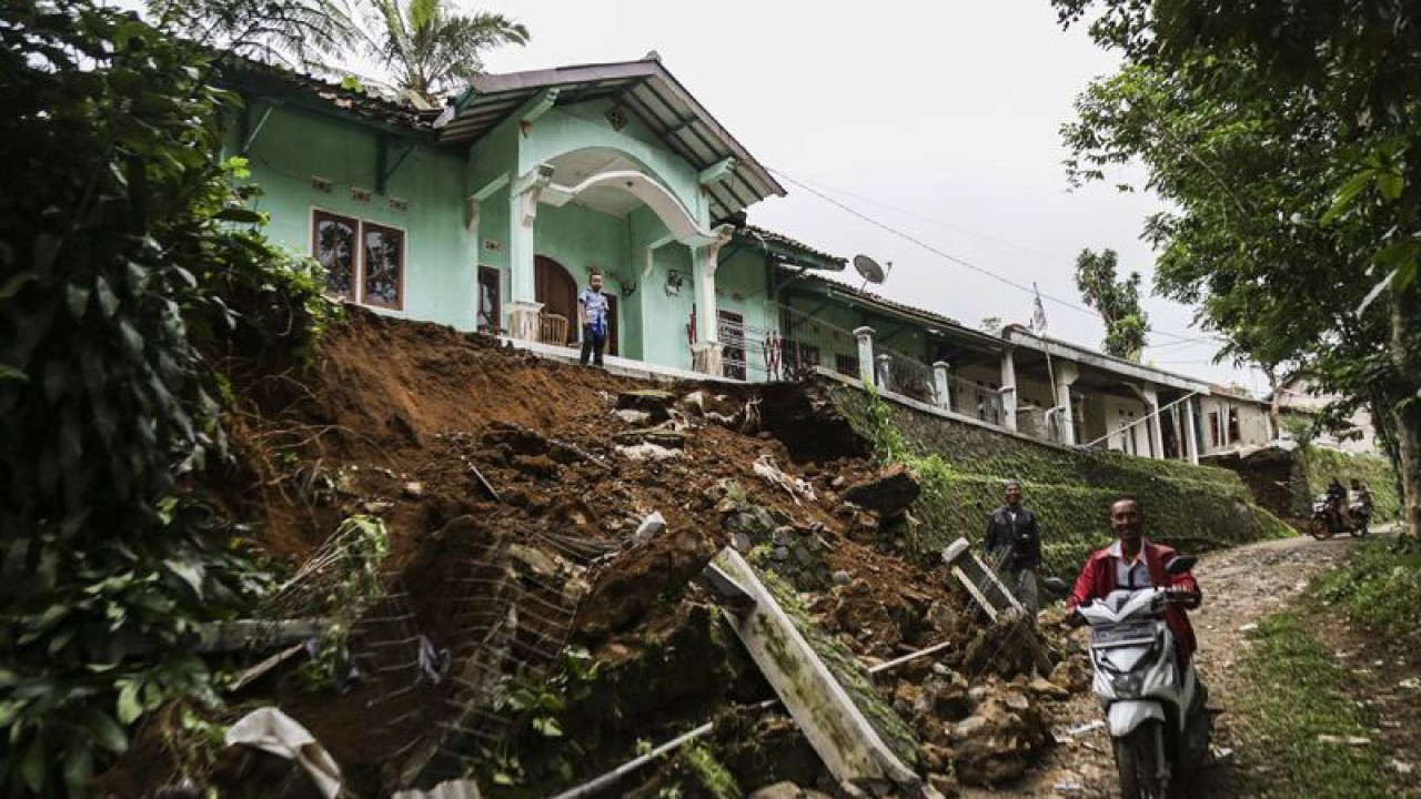 Warga melintas di reruntuhan tanah di Pasir Masigit, Desa Cipeuteuy, Kabandungan, Kabupaten Sukabumi, Jawa Barat, Sabtu (9/12/2023). ANTARA FOTO/Henry Purba/agr/YU/am.