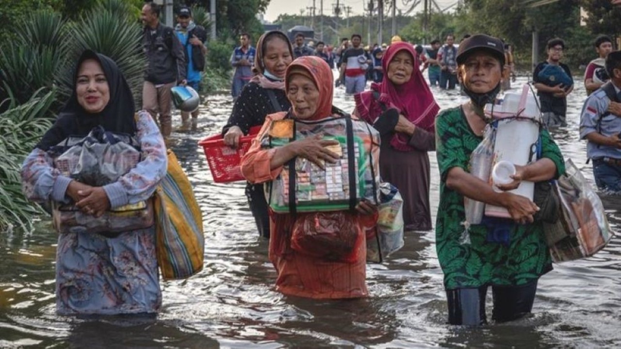 Sejumlah pedagang asongan pelabuhan berjalan menembus banjir limpasan air laut ke daratan atau rob yang merendam kawasan Pelabuhan Tanjung Emas Semarang, Jawa Tengah, Senin (23/5). (Antara)
